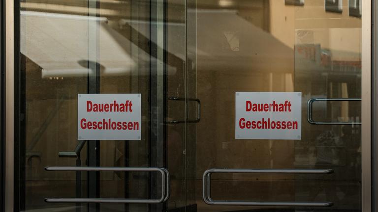 Ein Schild mit der Aufschrift "Dauerhaft Geschlossen" an einer Glastür