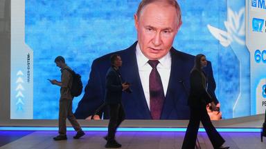 Menschen gehen an einem Bildschirm mit einem Bild des russischen Präsidenten Wladimir Putin auf dem Internationalen Wirtschaftsforum in St. Petersburg, Russland, am Mittwoch, dem 3. Juni 2026, vorbei. (AP Foto/Dmitri Lovetsky)