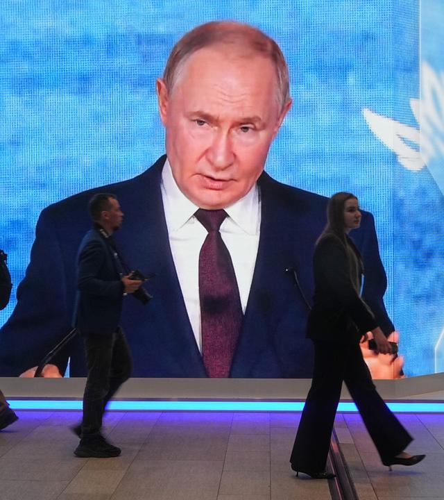 Menschen gehen an einem Bildschirm mit einem Bild des russischen Präsidenten Wladimir Putin auf dem Internationalen Wirtschaftsforum in St. Petersburg, Russland, am Mittwoch, dem 3. Juni 2026, vorbei. (AP Foto/Dmitri Lovetsky)