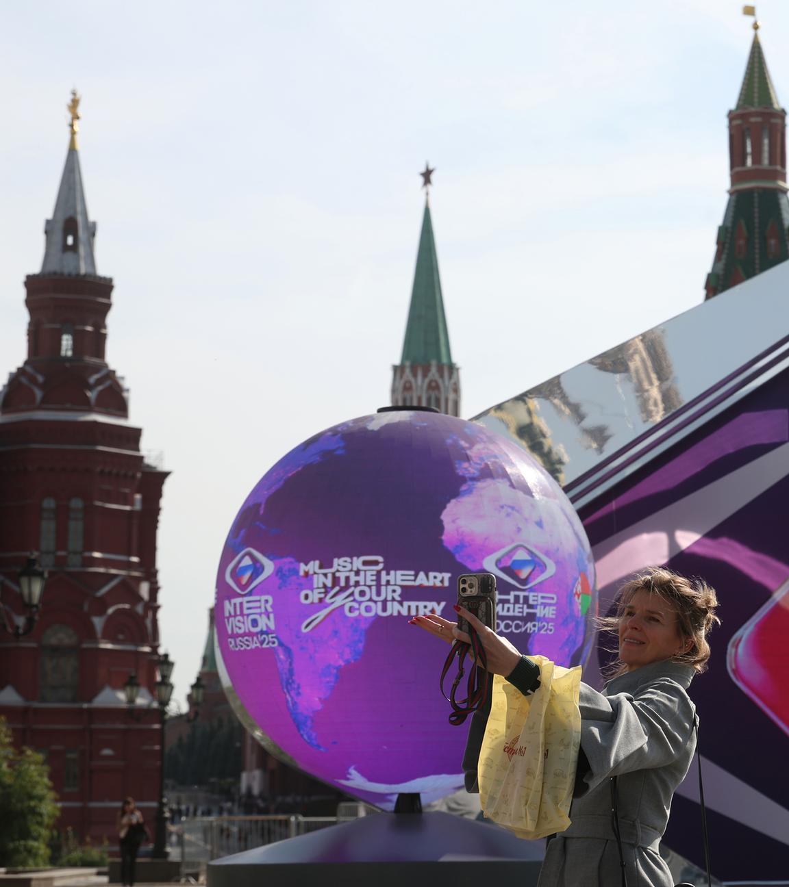 Eine Frau geht an einem sonnigen Herbsttag in Moskau, Russland, am 17. September 2025 vor einer Installation, die dem Internationalen Musikwettbewerb „Intervision“ gewidmet ist, im Sarjadje-Park in der Nähe des Kremls. 
