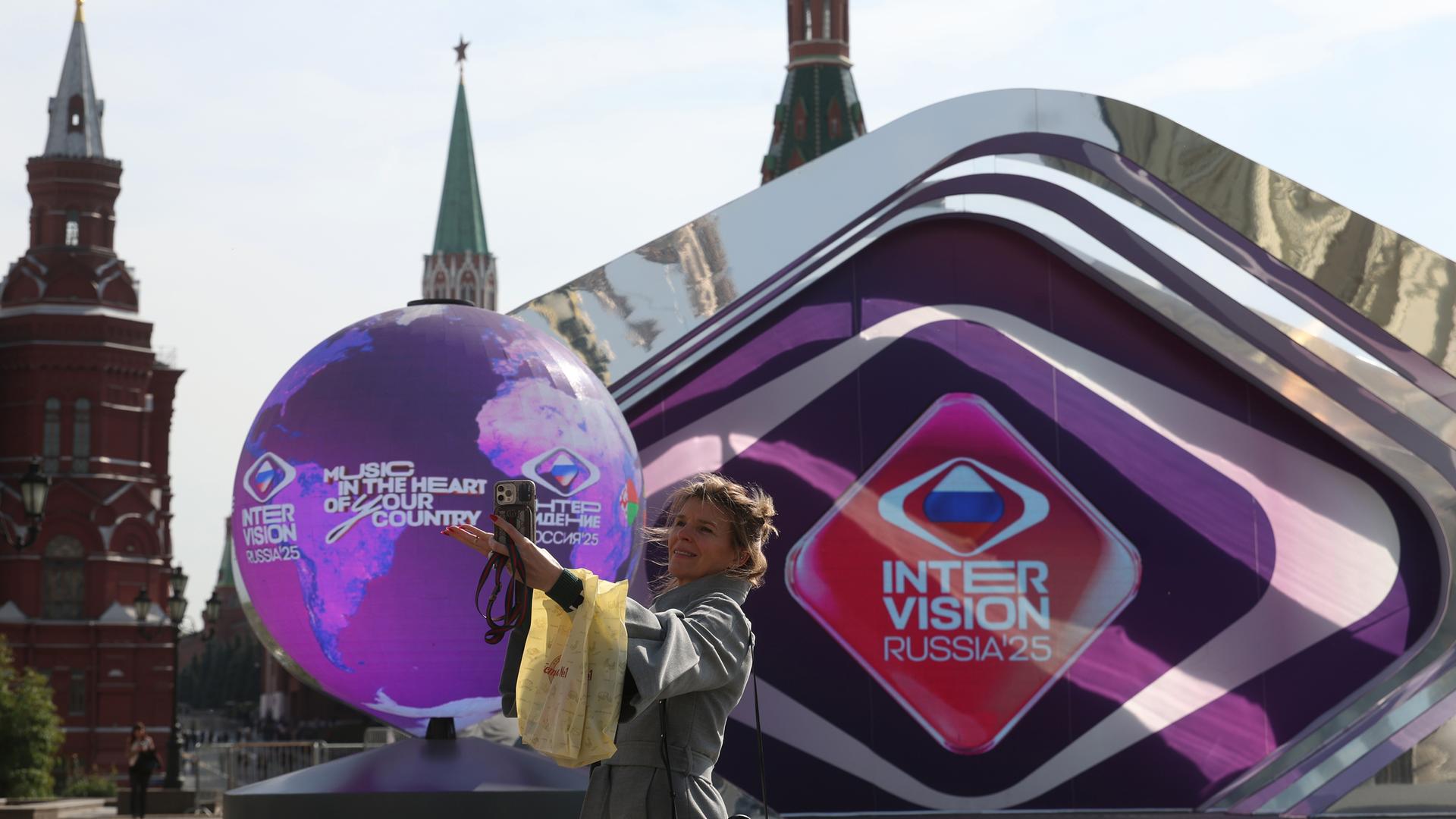 Eine Frau geht an einem sonnigen Herbsttag in Moskau, Russland, am 17. September 2025 vor einer Installation, die dem Internationalen Musikwettbewerb „Intervision“ gewidmet ist, im Sarjadje-Park in der Nähe des Kremls. 