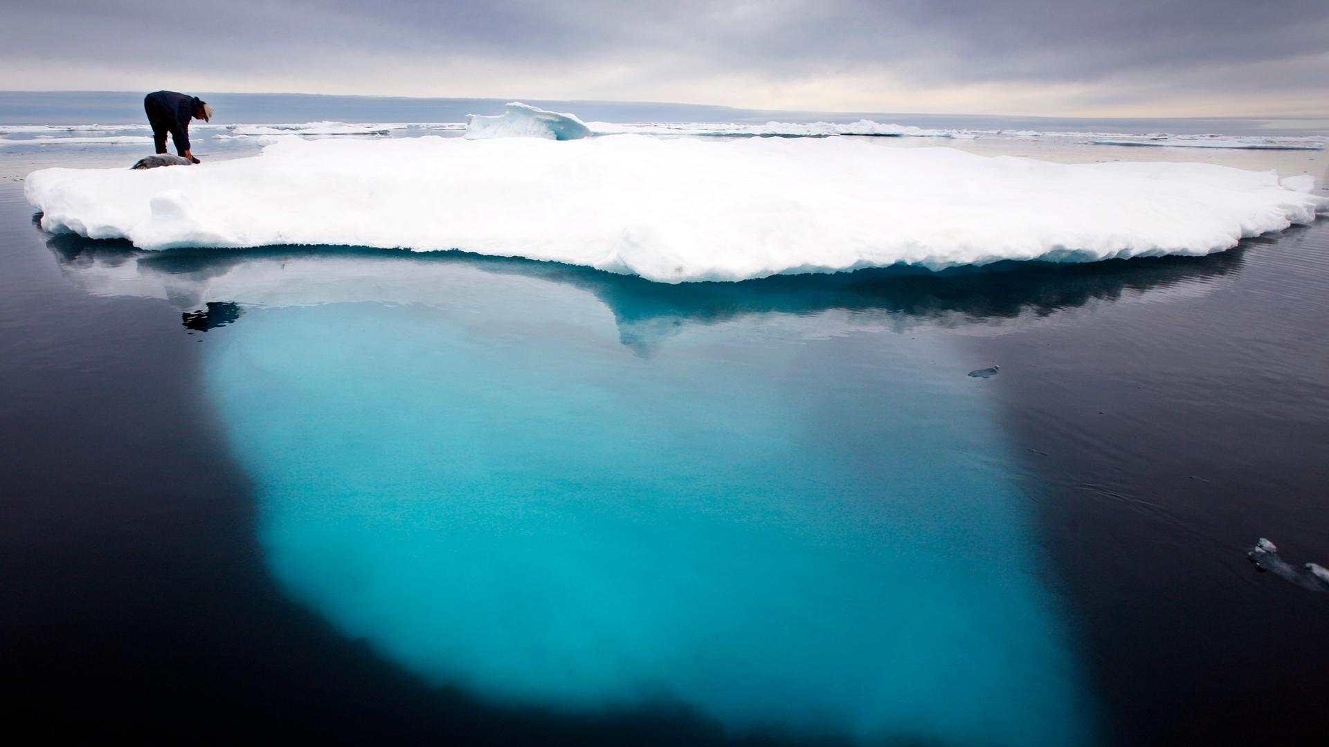 Ein Inuit auf einer Scholle von Meereis.