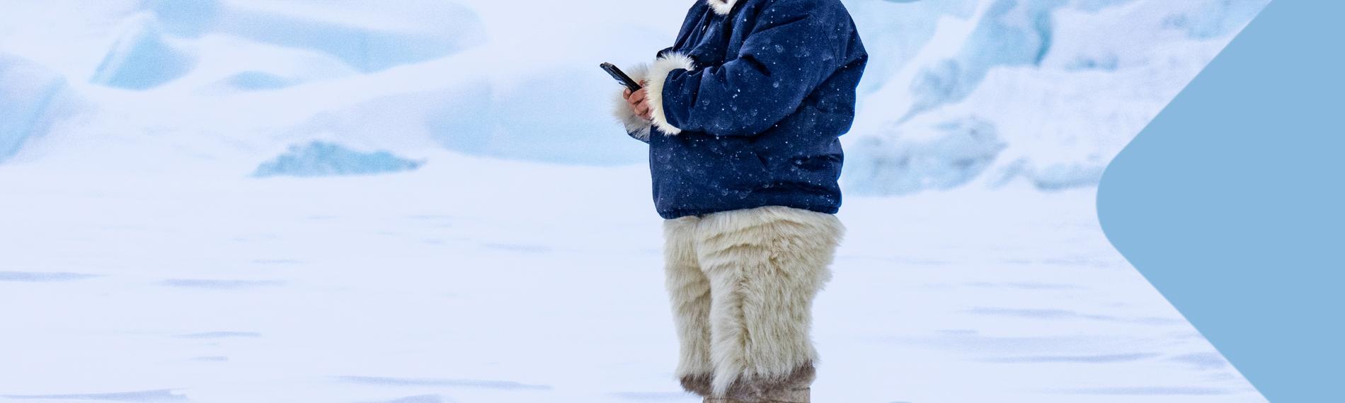 Inuit mit Smartphone in Eislandschaft