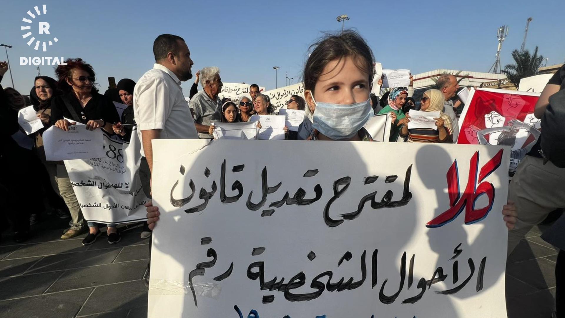 Ein Kind hält bei Protesten im Irak ein Plakat hoch.