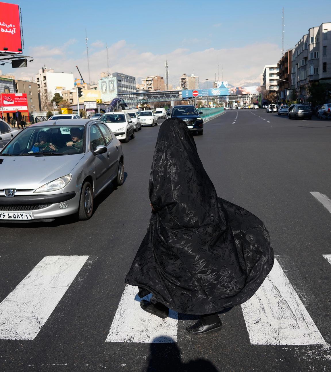 Eine Frau überquert eine Kreuzung in der Innenstadt von Teheran.