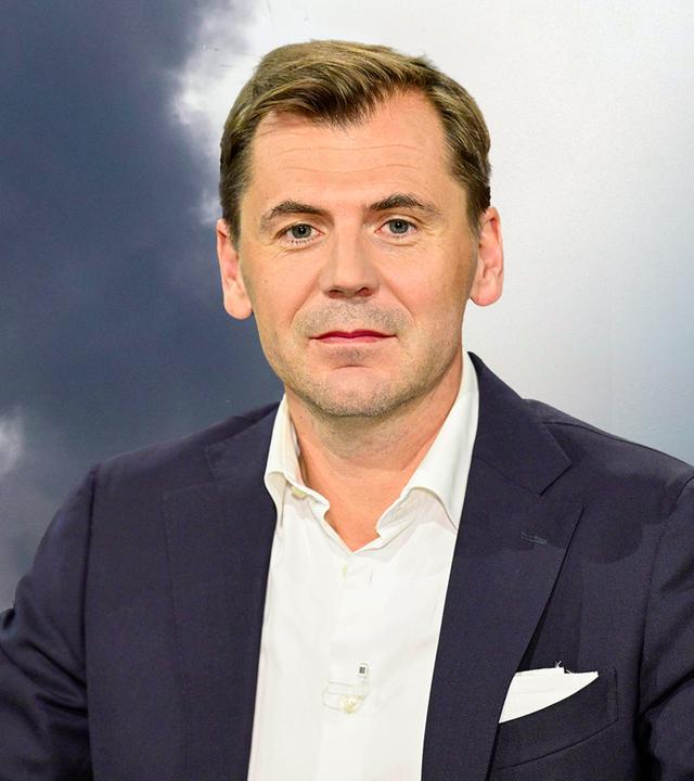 Links sind Rauchwolken zu sehen und rechts der Nahostexperte Daniel Gerlach.