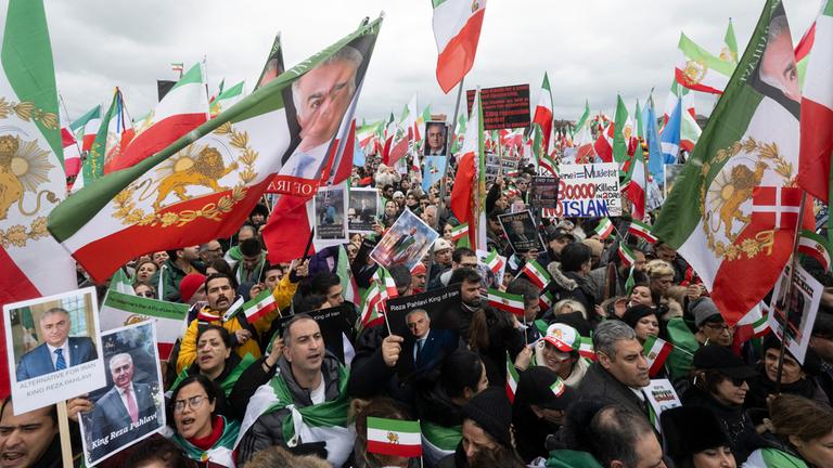 Teilnehmende einer Demonstration «Menschenrechte und Freiheit im Iran. Internationale Solidarität mit dem iranischen Volk» anlässlich der Münchner Sicherheitskonferenz stehen auf der Theresienwiese.