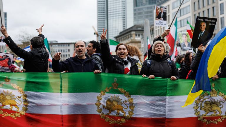  Teilnehmer halten Flaggen der iranischen Monarchie und zeigen das Victory-Zeichen auf der "Friedliche Demonstration und Aufzug für Freiheit und Demokratie im Iran" Demonstration in Frankfurt am Main.