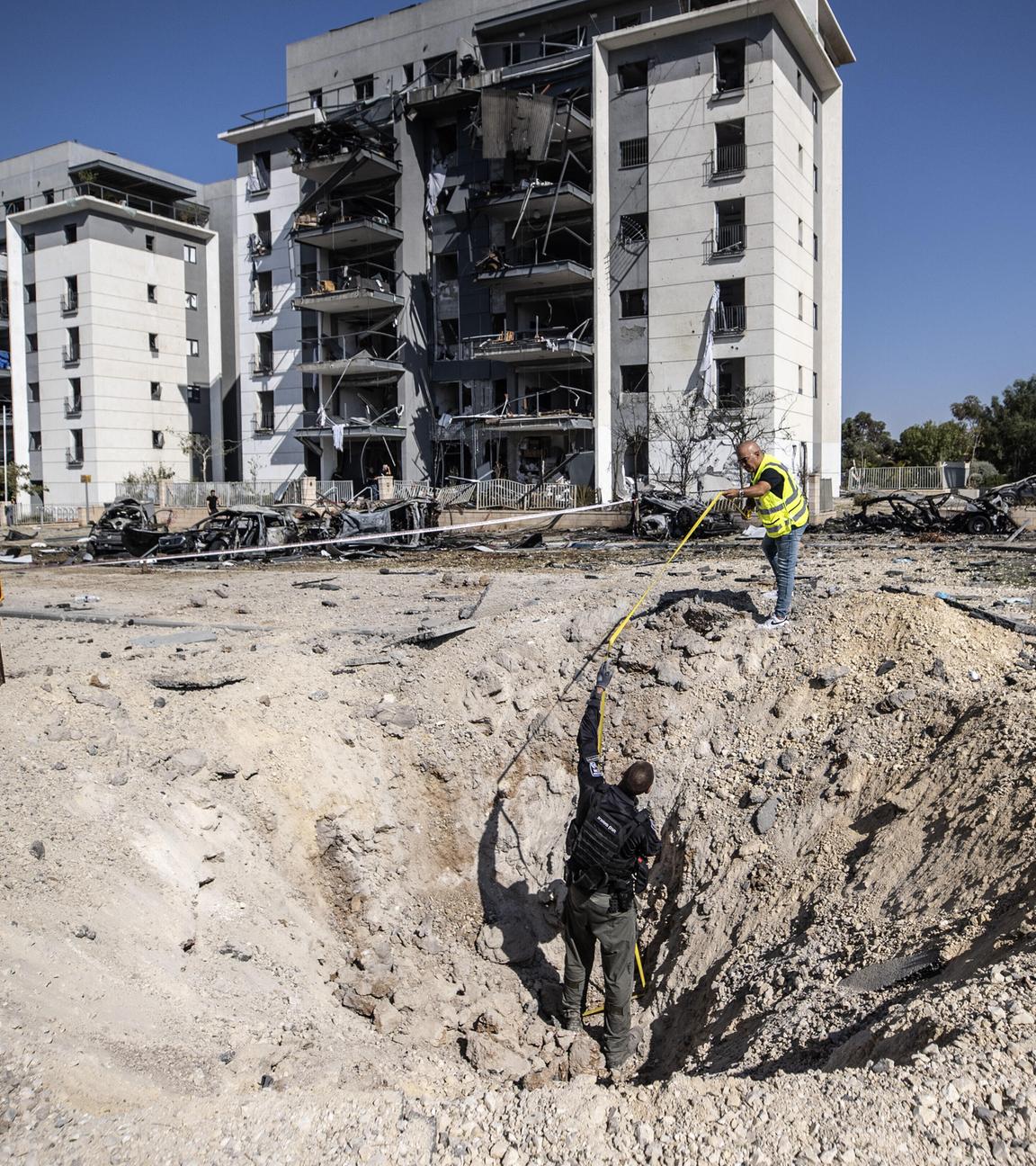 Israelische Polizeibeamte und Bombenentschärfungsexperten sind bei der Arbeit an der Einschlagstelle zu sehen, nachdem eine angeblich aus dem Iran abgefeuerte Rakete am 20. Juni 2025 in der südisraelischen Stadt Beersheba eingeschlagen ist.
