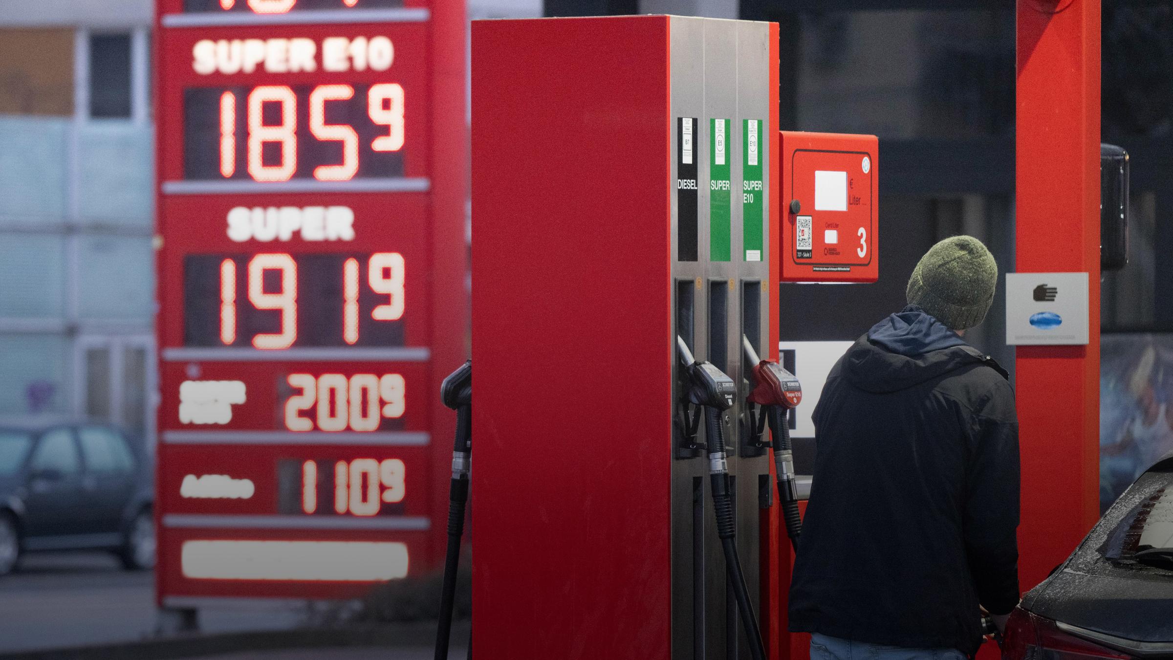 Sachsen, Dresden: Ein Mann betankt an einer Tankstelle vor einer Preistafel ein Auto.