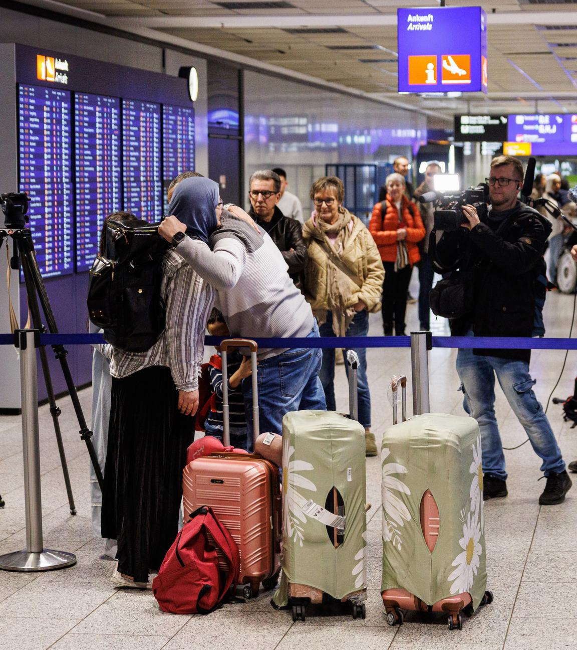 Menschen begrüßen sich nach ihrer Ankunft am Frankfurter Flughafen. 