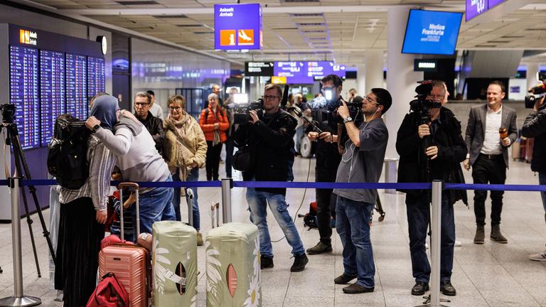 Menschen begrüßen sich nach ihrer Ankunft am Frankfurter Flughafen. 