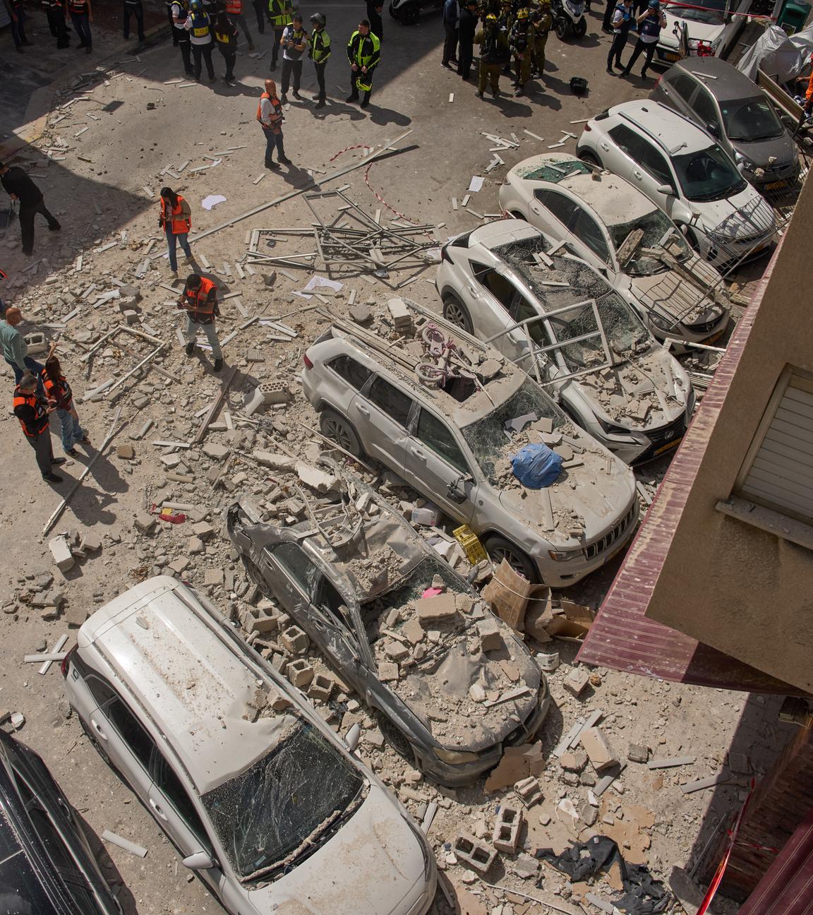 Israel, Ramat Gan: Die israelische Polizei inspiziert den Schaden an Autos und einem Wohnhaus.
