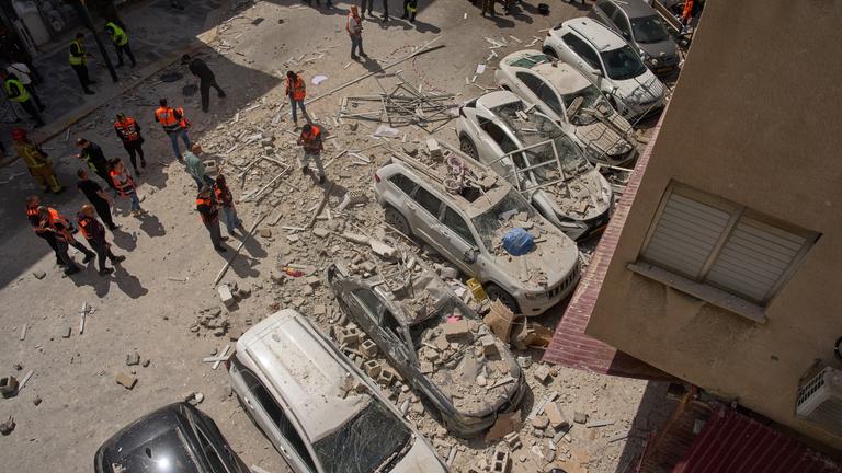 Israel, Ramat Gan: Die israelische Polizei inspiziert den Schaden an Autos und einem Wohnhaus.