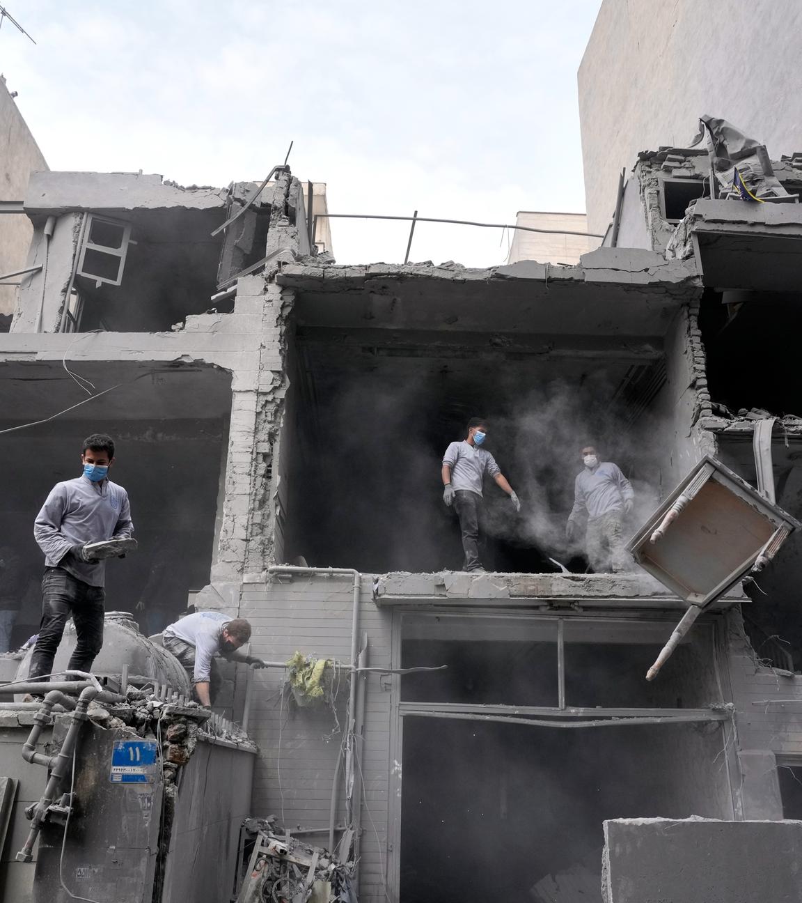 Menschen stehen in einer durch Krieg zerstörten Ruine im iranischen Teheran