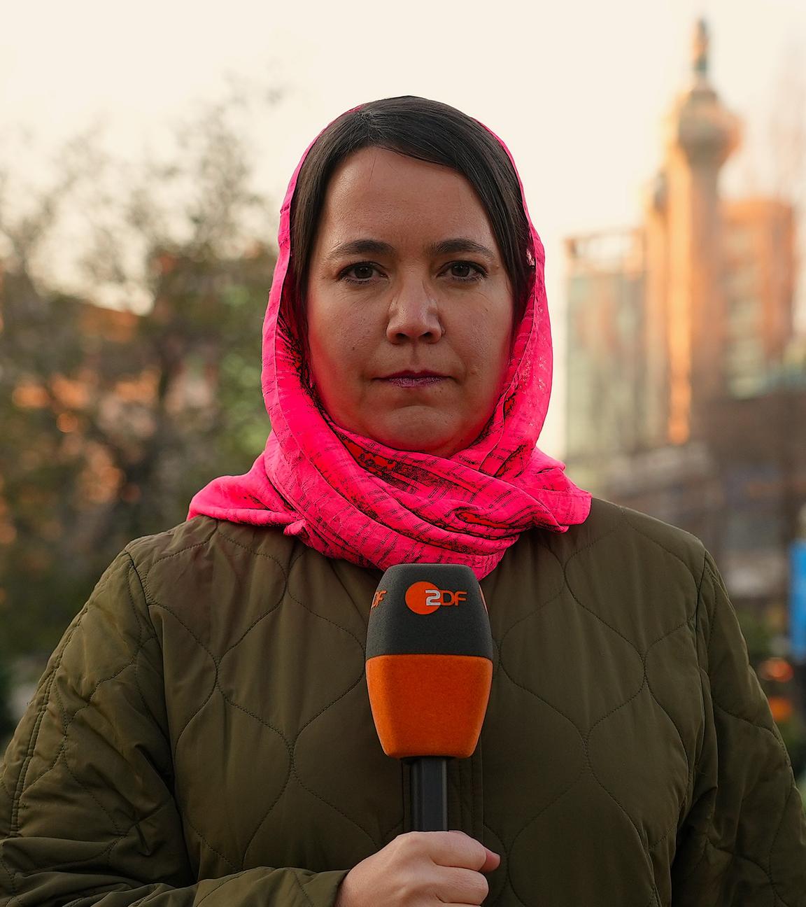 Phoebe Gaa mit Tuch um den Kopf gebunden mit Mikrofon in der Hand