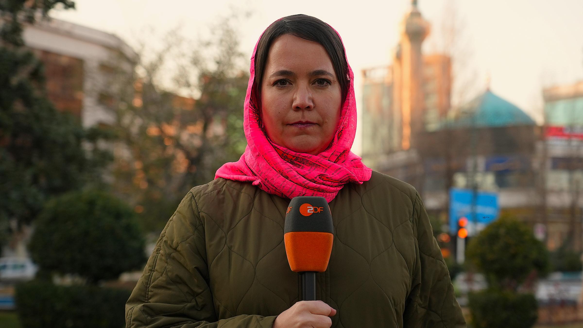 Phoebe Gaa mit Tuch um den Kopf gebunden mit Mikrofon in der Hand