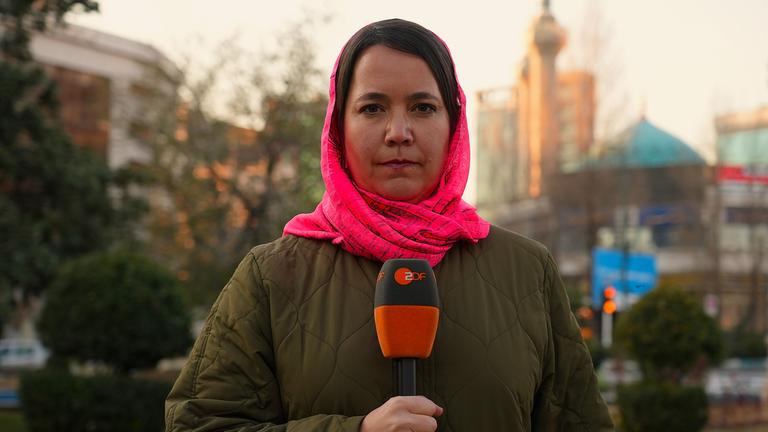 Phoebe Gaa mit Tuch um den Kopf gebunden mit Mikrofon in der Hand