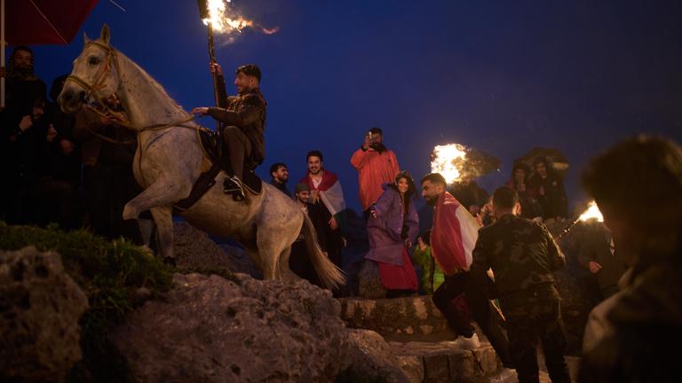 Ein kurdischer Mann reitet während des persischen Neujahrsfestes Nowruz in der Stadt Akra in der autonomen Region Kurdistan im Irak auf einem Pferd einen Hügel hinauf und trägt eine brennende Fackel.