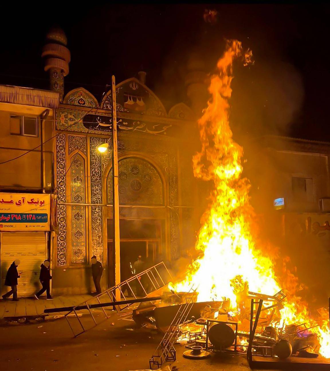 Flammen steigen am 10. Januar 2026 aus brennenden Trümmern mitten auf einer Straße in Gorgan auf.