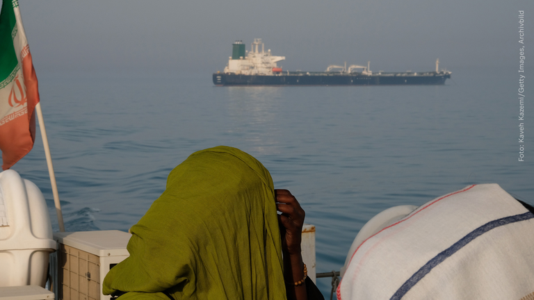 Frauen auf Boot mit Blick auf ein großes Schiff. 
