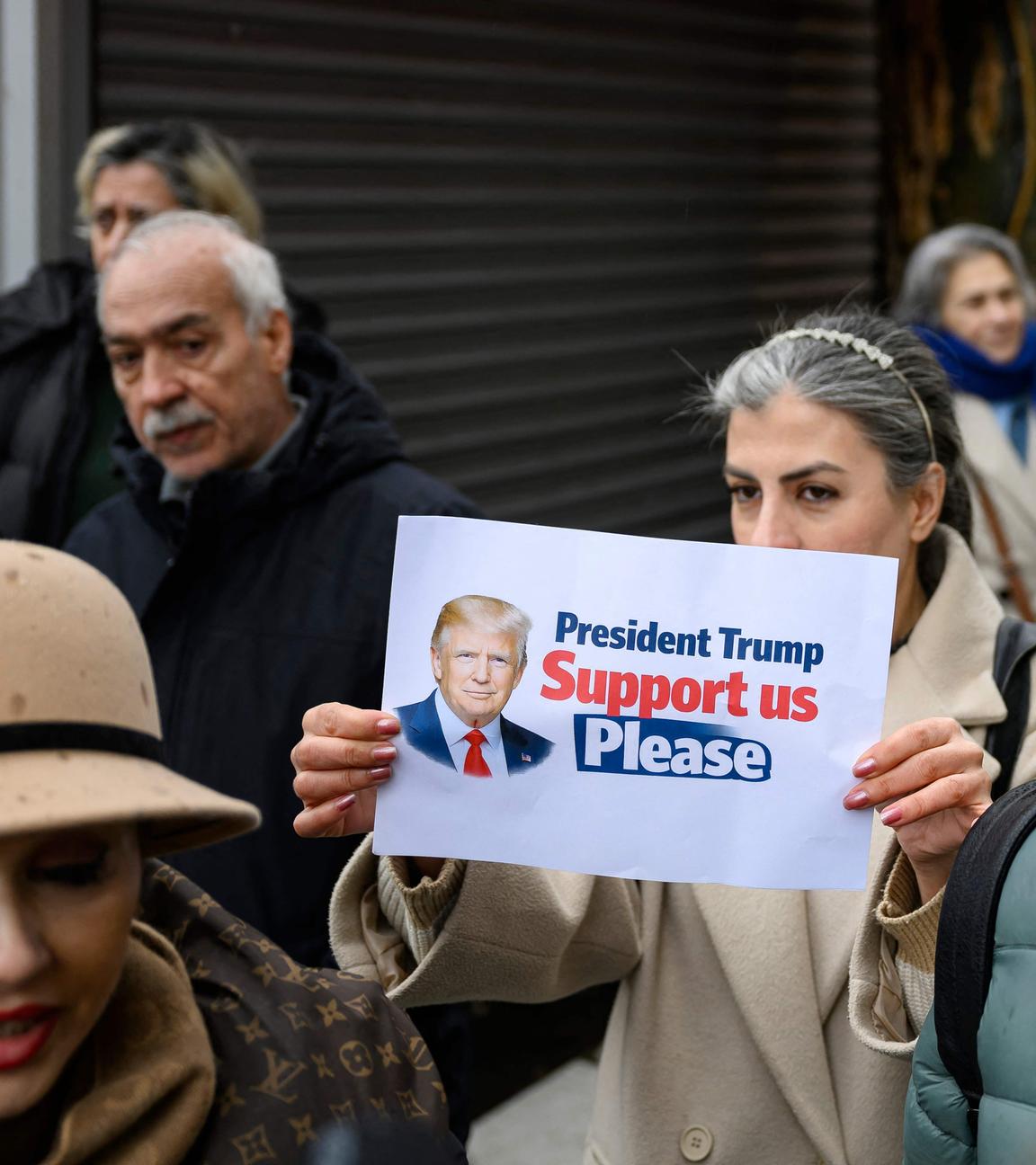 Menschen protesiteren vor dem iranischen Konsulat in Istanbul. Auf einem Bild ist US-Präsident Trump abgebildet mit der Aufschrift "President Trump Support us please".