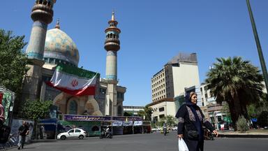 Eine Frau geht in Teheran über eine Straße.