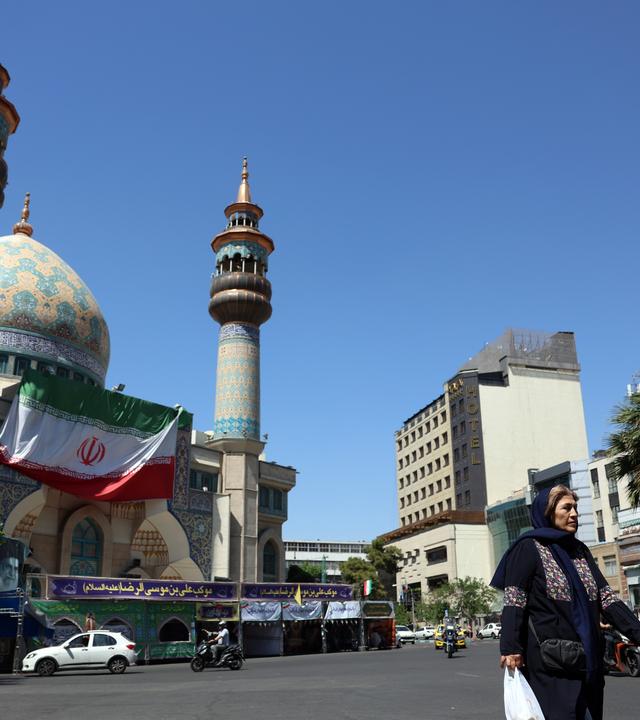 Eine Frau geht in Teheran über eine Straße.