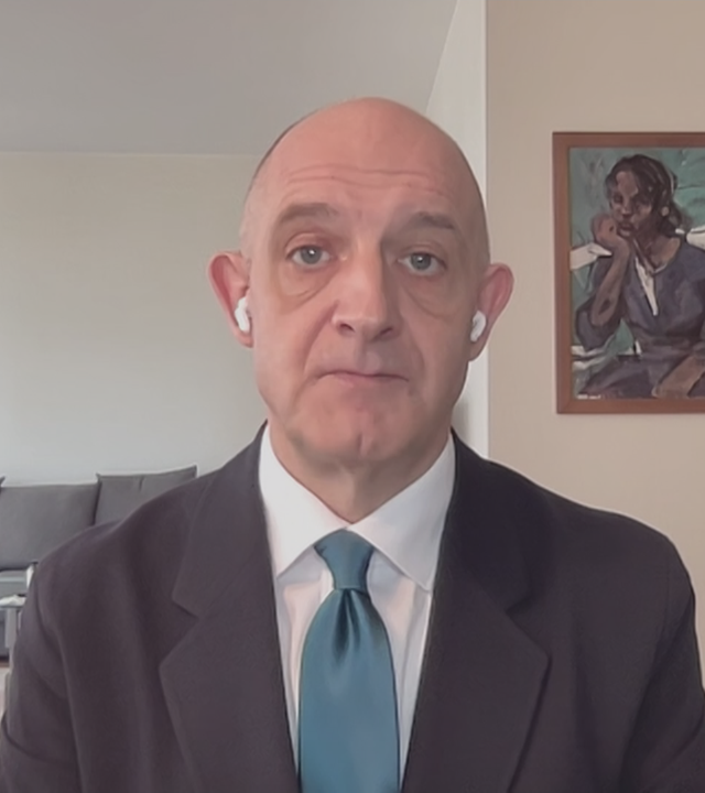 Nah-Ost Experte Hans-Jakob Schindler per Videocall zugeschaltet aus seinem Wohnzimmer; links hinten ist eine Couch zu sehen und rechts an einer Wand ein Gemälde