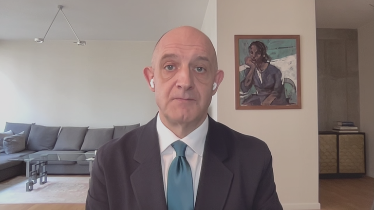 Nah-Ost Experte Hans-Jakob Schindler per Videocall zugeschaltet aus seinem Wohnzimmer; links hinten ist eine Couch zu sehen und rechts an einer Wand ein Gemälde