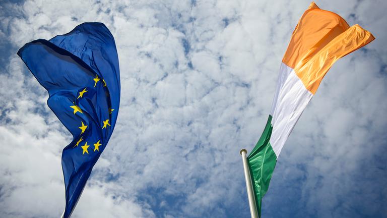 Flaggen der EU und Irland wehen am Himmel