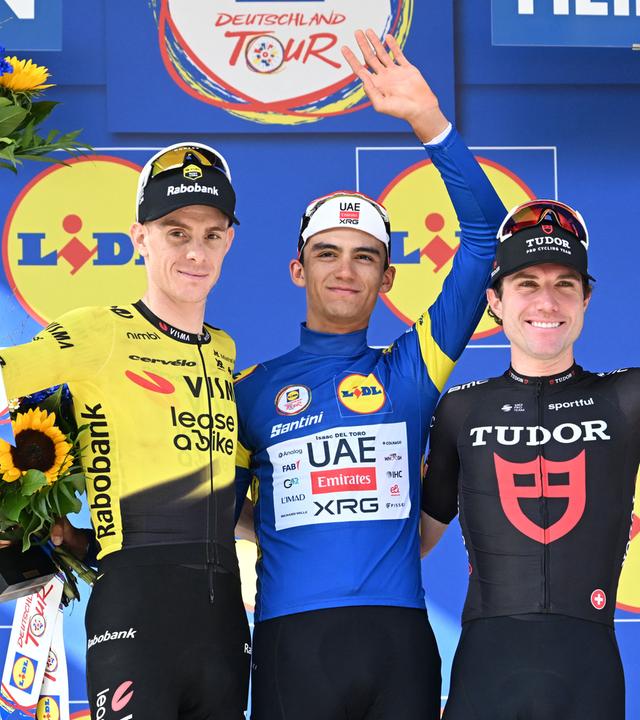 Gesamtsieger Isaac del Toro (Mexiko, M) jubelt mit Louis Barré (Frankreich, l.) und Marc Hirschi (Schweiz, r.) über die Podiumsplätze der Deutschland Tour.