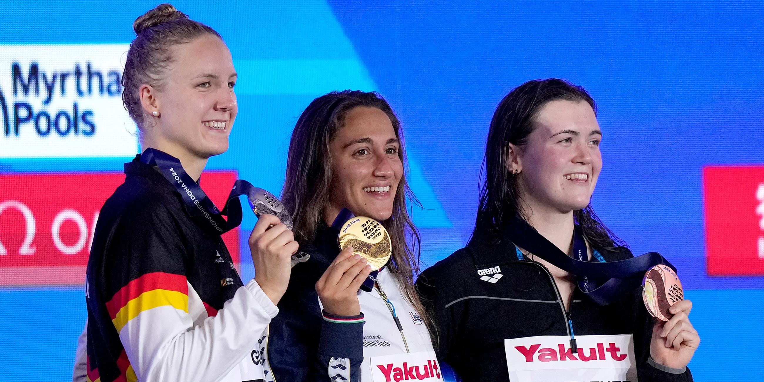 Die Goldmedaillengewinnerin Simona Quadarella (M) aus Italien, die Silbermedaillengewinnerin Isabel Gose aus Deutschland (l) und die Bronzemedaillengewinnerin Erika Fairweather aus Neuseeland posieren für ein Foto während der Medaillenzeremonie.