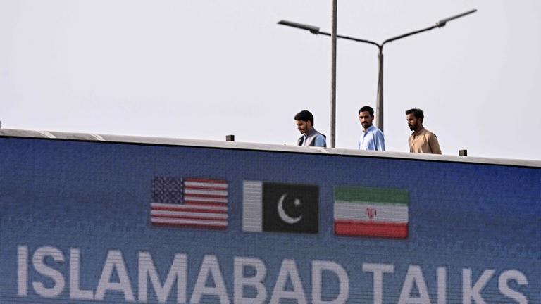 Youth walk behind a digital screen displaying news of USIran peace talks along a road in Islamabad on April 10, 2026.