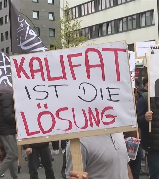 Demonstraten mit Plakat mit Aufschrift "Kalifat ist die Lösung".