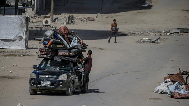 Eine Auto mit Habseligkeiten auf dem Dach festgeschnürt fährt durch Gaza-Stadt.