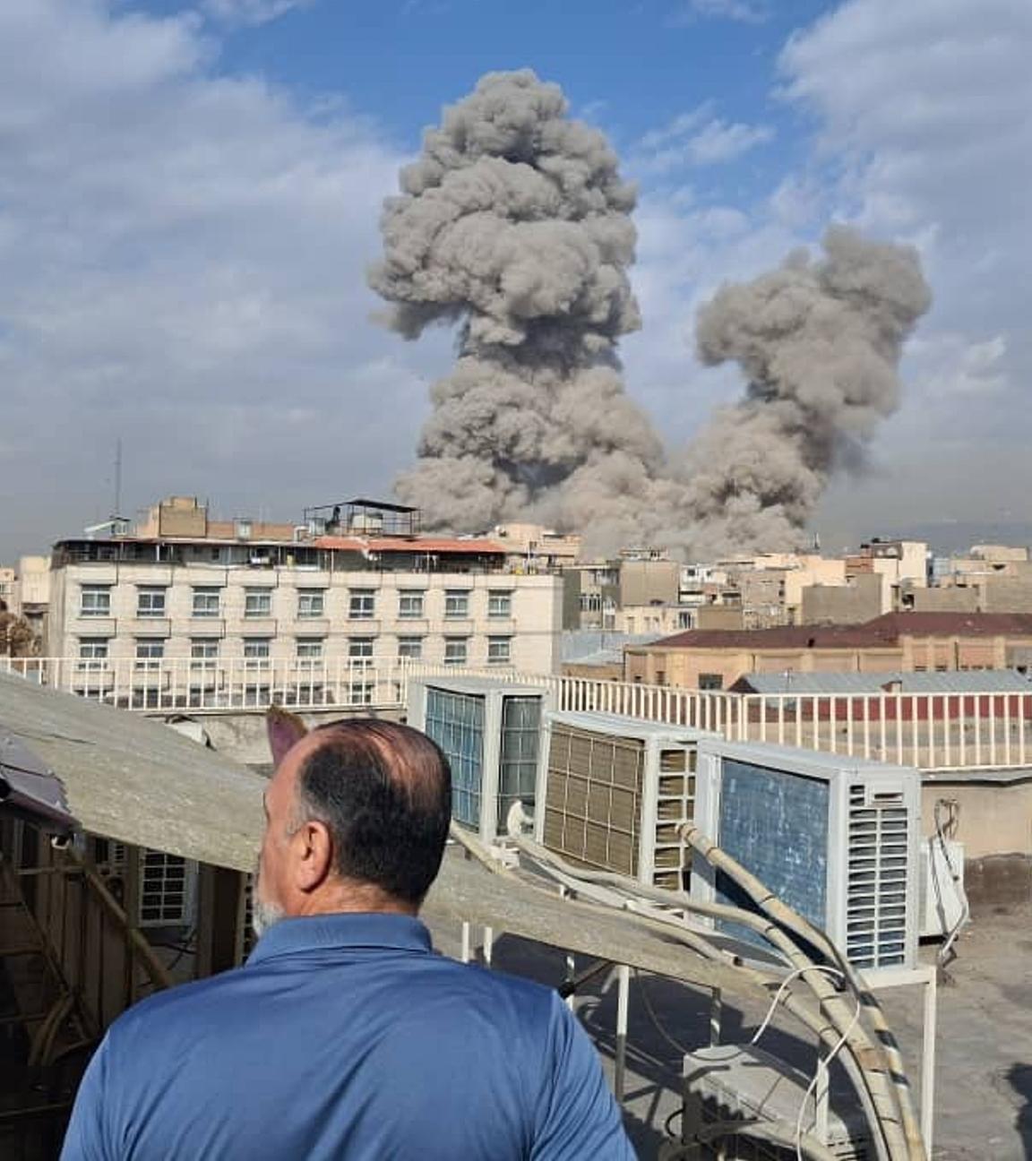 Menschen beobachten Rauch nach einer Explosion in Teheran.