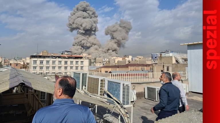 Menschen beobachten Rauch nach einer Explosion in Teheran.