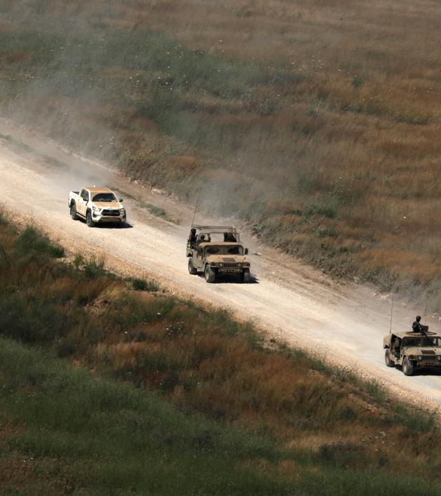 Fahrzeuge der israelischen Armee fahren auf einer Straße auf der libanesischen Seite der Grenze.