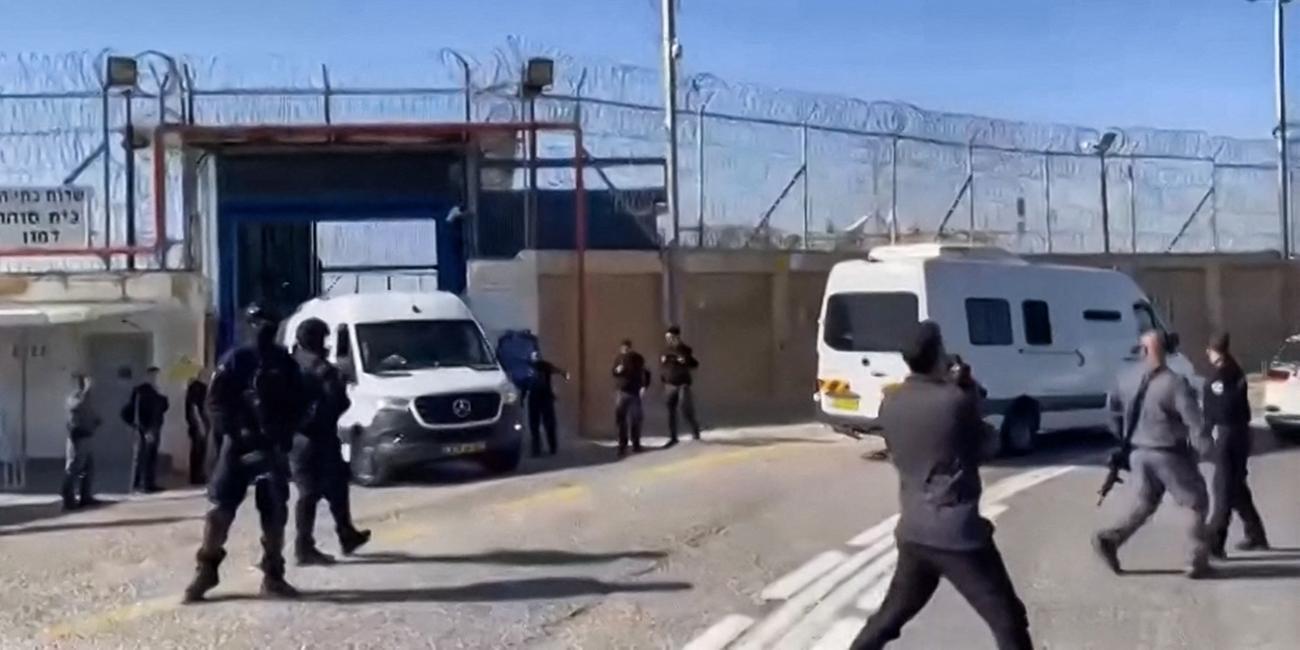 Mehrere Sicherheitskräfte stehen vor den Gefängnistoren durch die zwei Minibusse die Anlage verlassen.