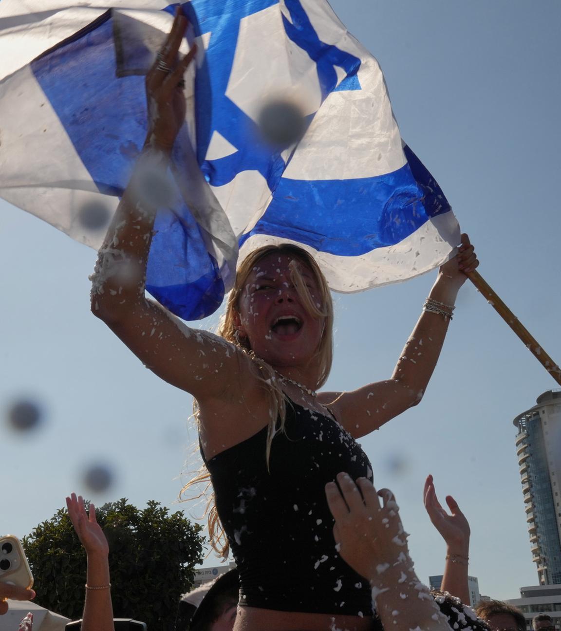 Menschen halten die israelische Flagge und versprühen Schaum, um die Ankunft der befreiten Geiseln im Beilinson-Krankenhaus in Petah Tikva, Israel, zu feiern.