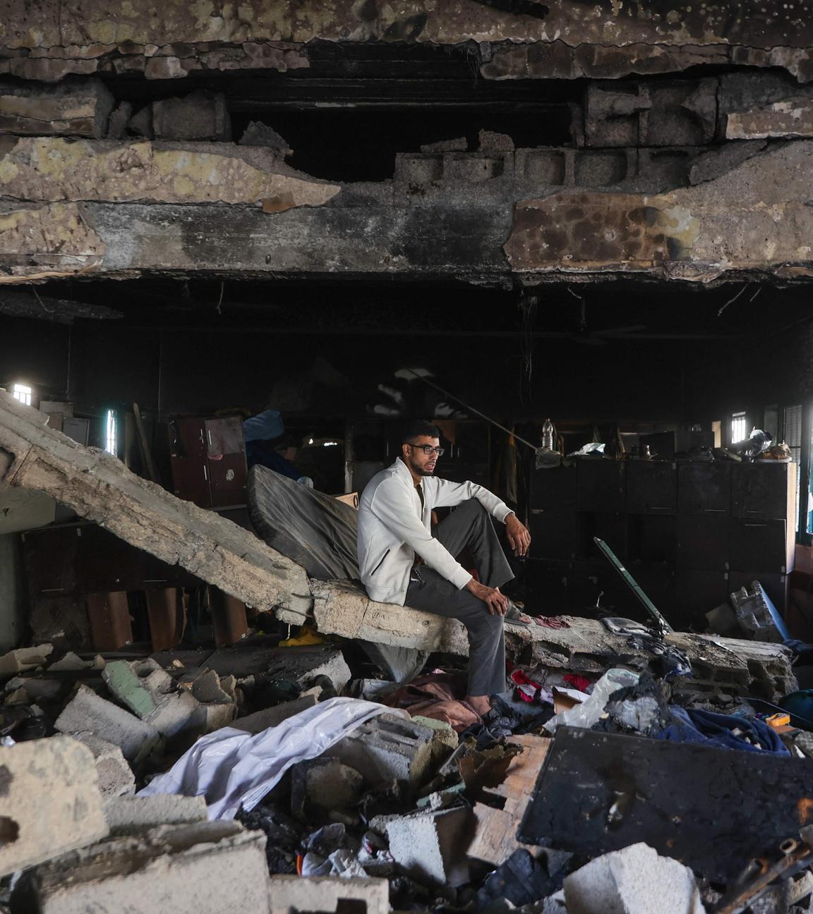 Ein palästinensischer Mann istzt auf Trümmern in der zerstörten Fahmi Al-Jarjawi Schule in Gaza-Stadt im Gazastreifen. Die Schule, die als Notunterkunft genutzt wurde, wurde bei einem israelischen Luftangriff zerstört.