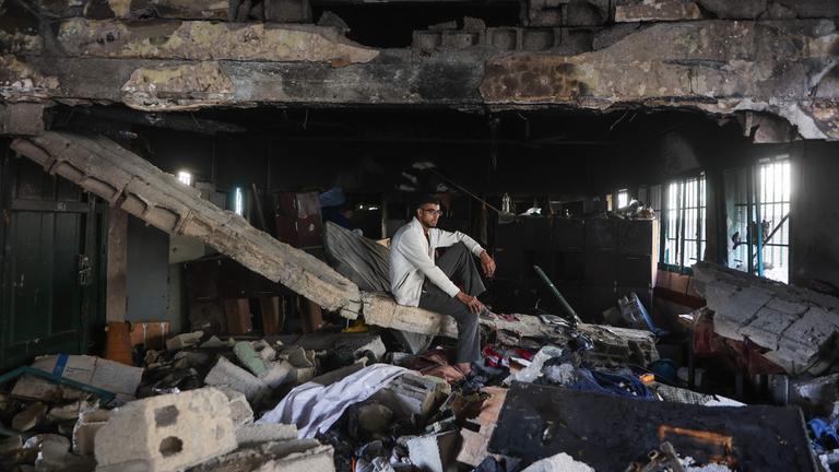 Ein palästinensischer Mann istzt auf Trümmern in der zerstörten Fahmi Al-Jarjawi Schule in Gaza-Stadt im Gazastreifen. Die Schule, die als Notunterkunft genutzt wurde, wurde bei einem israelischen Luftangriff zerstört.