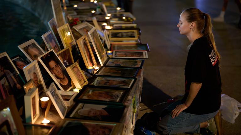 Eine Frau kniet in Tel Aviv vor einer Gedenkstätte mit Bildern der Opfer vom 7. Oktober 2023.