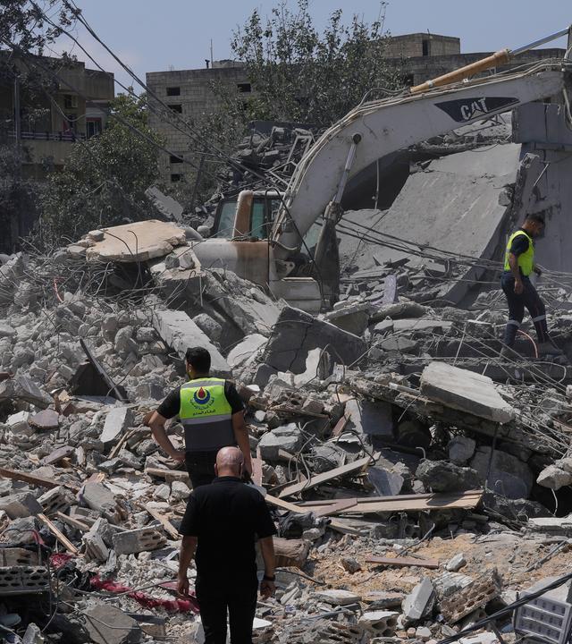Menschen und Rettungskräfte versammeln sich vor einem zerstörten Haus, das von einem israelischen Luftangriff getroffen wurde. 