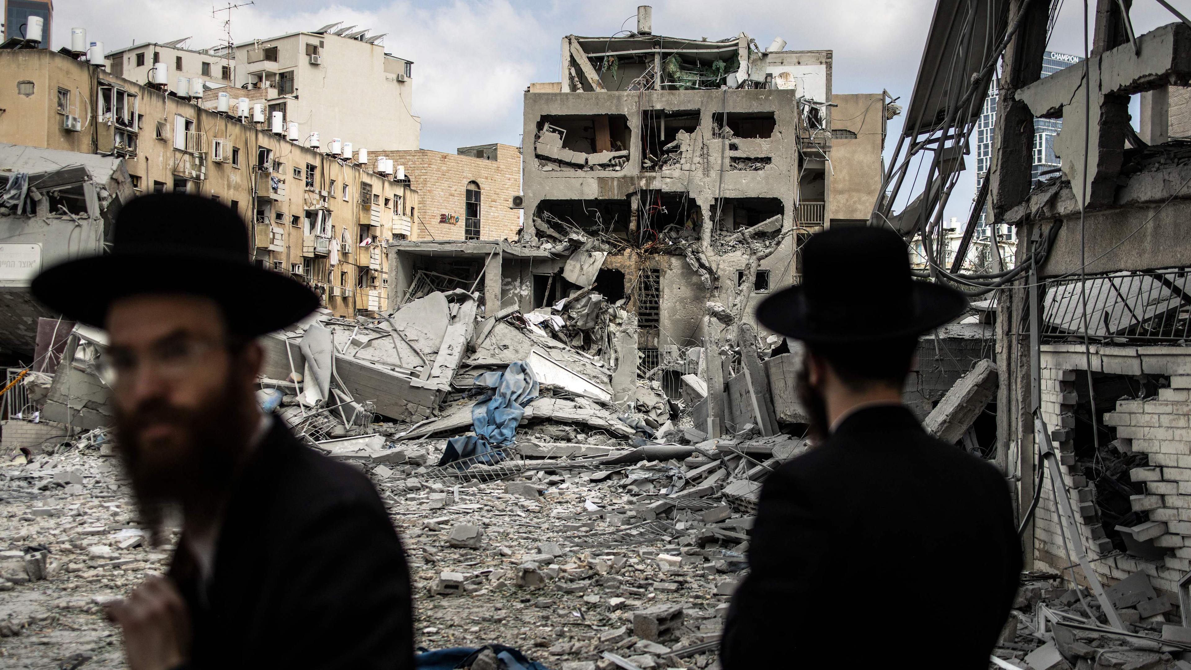 Orthodoxe Männer stehen vor zerstörten Häusern in Bnei Brak, Israel