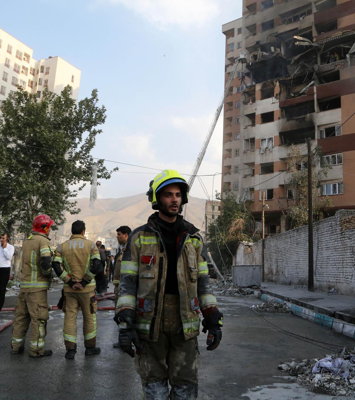 Feuerwehrleute stehen vor einem zerstörten Haus in Teheran.
