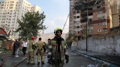 Feuerwehrleute stehen vor einem zerstörten Haus in Teheran.
