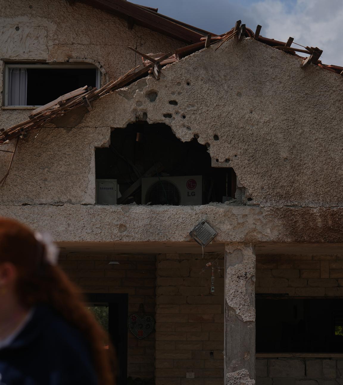 Eine Frau läuft an einem schwer beschädigten Haus vorbei.