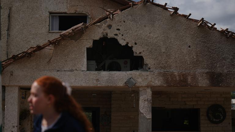 Eine Frau läuft an einem schwer beschädigten Haus vorbei.